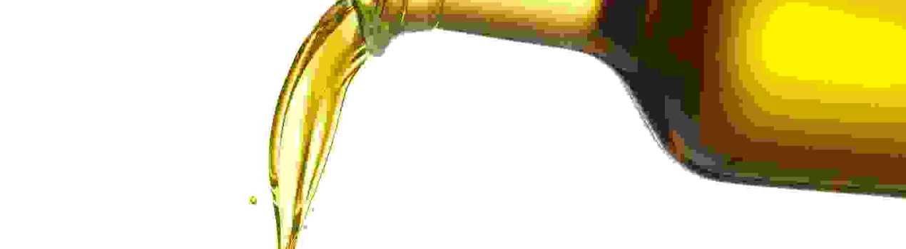 pouring olive oil from glass bottle against white background